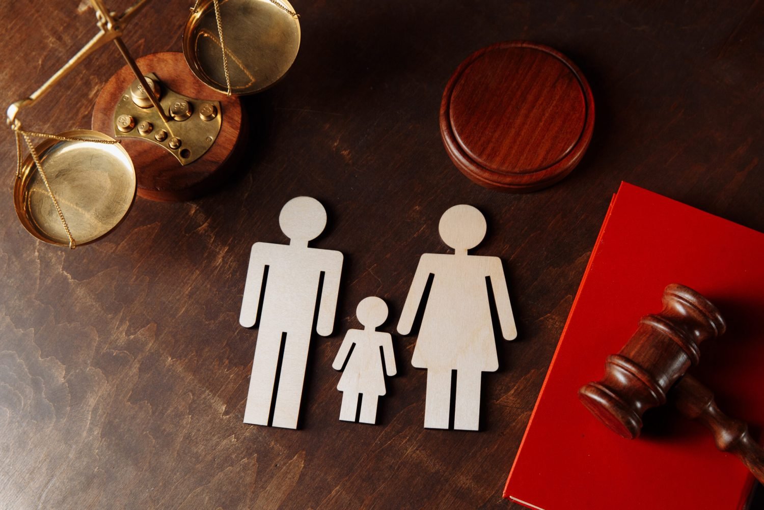 Judge's gavel on a red book and family figures.